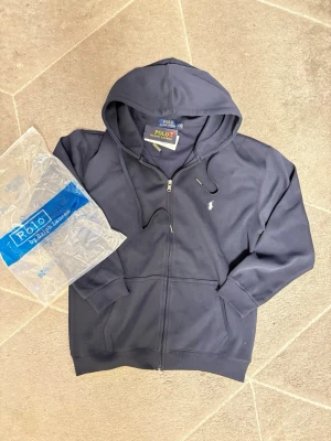 Ralph lauren - Helt ny ralph lauren kofta i mörkblå. Den är oanvänd och koftan kommer med allt som finns med i första bilden. Storleken är L med rekommenderar mindre storlek för bättre passform. Skriv för information.