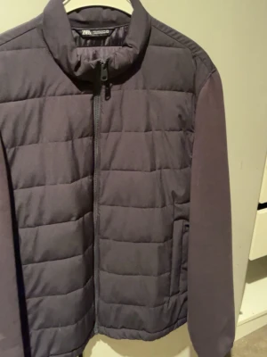 Mörkblå Cardigan från Zara - Snygg mörkblå pufferjacka från Zara med quiltad framsida och släta ärmar. Jackan har hög krage, dragkedja framtill och två sidofickor. Perfekt för kalla dagar när du vill hålla stilen enkel och clean. Storlek L och M 