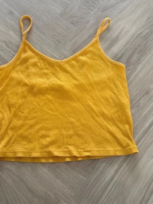Gul ribbad crop top från FB Sister - Snygg gul crop top från FB Sister i ribbat tyg. Toppen har smala axelband och en figurnära passform, perfekt för varma dagar eller lager på lager. Materialet är mjukt och stretchigt för extra komfort.