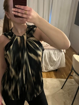 Svart och beige ärmlös blus - Säljer en snygg ärmlös blus med svart och beige mönster. 