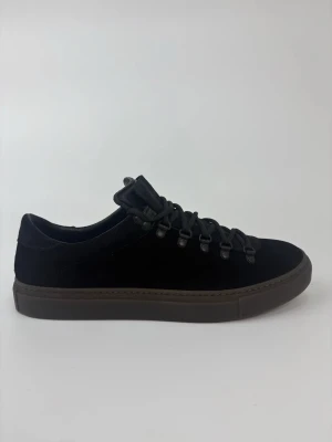 Svarta sneakers från Diemme i mocka - Stilrena svarta sneakers från Diemme i mjuk mocka med robusta svarta snören och mörkbrun sula. Skorna har en clean design med metallöglor och låg profil som passar perfekt till streetwear och vardagsstil.