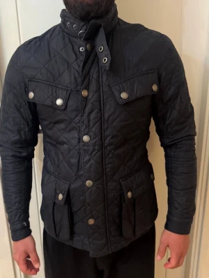 Babour jacka  - Snygg babour jacka med hög krage och tryckknappar framtill. Fyra fickor med lock och knappar ger en cool look. Jackan har lång ärm och figurnära passform, perfekt för dig som gillar stilrena och praktiska plagg. Priset går att diskutera 