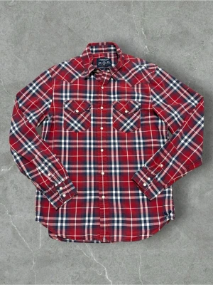 Flannel Skjorta Från American Eagle - Klassisk röd rutig skjorta från Gant med vita och blå detaljer. Skjortan har två bröstfickor med knappstängning, långa ärmar och vita knappar framtill. Perfekt för en avslappnad och stilren look.