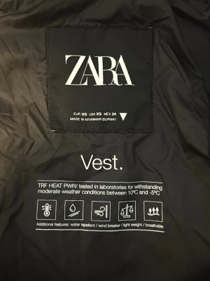 Svart väst från ZARA -  Svart dunväst från ZARA med luva. Västen är vattenavvisande, vindtät, lätt och andas. Modellen finns inte i sortiment längre köpt för ca 2 år sedan men i fint skick. 