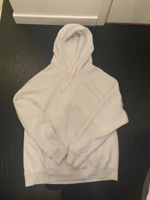 Vit hoodie från F2 Sister - Klassisk vit hoodie från F2 Sister med huva och dragsnören. Mjuk insida och stor känguruficka framtill. Perfekt för en avslappnad och stilren look. Tillverkad i bomullsblandning för extra komfort.