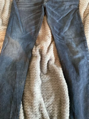 Mörkblå diesel jeans - Snygga mörkblå jeans med rak passform och klassisk femficksdesign. Jeansen har subtila slitningar och är tillverkade i denim. Perfekta för en avslappnad och stilren look.       Diesel.    W32.   L32 