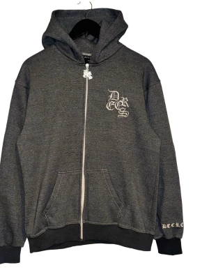 Decrese Sweden hoodie – oanvänd (M) - Antracitgrå hoodie med vita detaljer i premiumkvalitet. Dragkedja, två fickor, vit logga fram, brodyr bak och broderad drake på huvan. Unisex, stilren och bekväm. Mått: Axel 51, bröst 51, längd 67, ärm 61 cm.                                             📦Leverans: Skickas inom 1–2 dagar ⚠️ Observera: Köparen står för returfrakt. Vid byte även ny frakt. Storleken kan variera med cirka 1–3 cm på grund av manuella mätningar. ⚠️