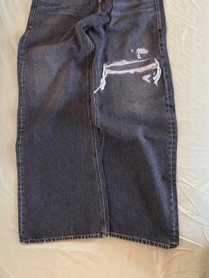 Diesel D Rise - Säljer ett par grå jeans från Diesel med raka ben och slitna detaljer på framsidan. Jeansen har klassisk femficksdesign och tydliga slitningar för en cool, avslappnad look. Perfekta för dig som gillar streetstyle och vintagekänsla.