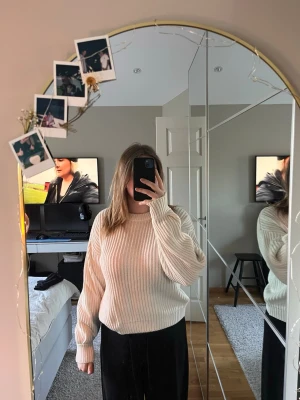 Beige ribbstickad tröja - En stilren beige ribbstickad tröja med rund hals och långa ärmar. Tröjan har en något lös passform och breda ribbade muddar vid ärmslut och nederkant. Perfekt för att skapa en avslappnad look.