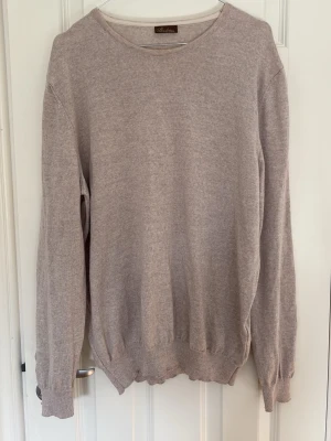 Beige stickad tröja från Stenströms - En stilren beige stickad tröja från Stenströms med rund halsringning och långa ärmar. Tröjan har ribbade muddar vid ärmslut och nederkant. Perfekt för lager-på-lager och enkel att matcha med olika outfits. Har en fläck på ena armbågen