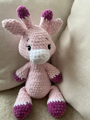Virkad giraff Rosa - En gullig rosa handvirkad giraff av mjukt chenillegarn. Mjukisdjuret är stoppad med polyesterfyllning och har säkerhetsögon av plast. Giraffen är ca 30 cm hög 🧶🦒OBS! Pga plastögonen rekommenderas inte mjukisdjuret för barn under 3 år