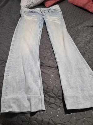 Ljusblå bootcut jeans från Weekday  - Snygga ljusblå jeans med bootcut-modell och klassisk femficksdesign. Jeansen har en låg midja och är tillverkade i mjukt denimtyg. Perfekta för dig som gillar en avslappnad och trendig stil. Använd fåtal gånger storlek 33/34 ljus/vit färge från weekday 