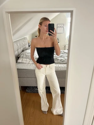 Svart tubtopp med subtilt mönster - Säljer en svart korsett med subtilt blommigt mönster. Toppen är axelbandslös och har en tight passform som framhäver siluetten. Perfekt för dig som vill ha en stilren och trendig look. Materialet känns mjukt och bekvämt mot huden.