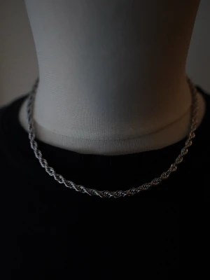Silverfärgat tvinnat halsband - Säljer ett stilrent halsband i silverfärg med tvinnad kedja. Halsbandet är i rostfritt stål,  och har en enkel design som passar till många olika stilar. Levereras i en svart tygpåse. Perfekt accessoar för dig som gillar minimalistiska smycken.                                                                Smycket är 4mm 45cm. 