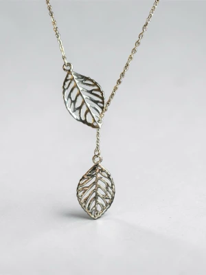 Silvrigt halsband med bladhängen - Snyggt halsband i silverfärgad metall med två detaljerade bladformade hängen. Kedjan är tunn och elegant, och bladen har ett öppet, luftigt mönster som ger en modern och stilren känsla. Perfekt för dig som gillar naturinspirerade accessoarer.