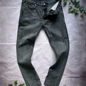 Svarta jeans från Nudie Jeans - Snygga svarta/grå jeans från Nudie Jeans med klassisk femficksdesign och diskret broderad bakficka. Jeansen har en slim passform och är i storlek W30 L30