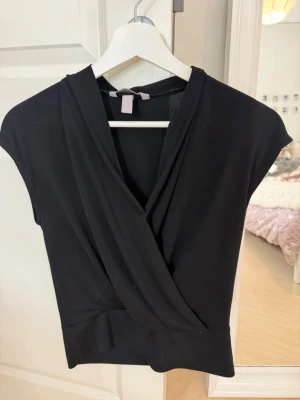 Svart omlottopp med v-ringning -  svart omlottopp med v-ringning och korta ärmar. 🖤