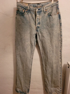 Levi's ljusblå mom jeans - Säljer ett par nya ljusblå 501s i klassisk 90's modell, från Levi's med medelhög midja och raka ben. Jeansen har fem fickor, knappgylf och den ikoniska röda Levi's-lappen bak. Tillverkade i slitstark denim som ger en vintagekänsla. Jeansen är tvättade en gång.