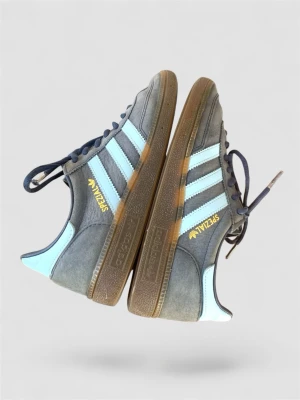 Adidas Spezial gråblå sneakers - Snygga Adidas Spezial sneakers i grå mocka med ljusblå detaljer och klassiska tre ränder på sidorna. Skorna har bruna gummisulor och mörkblå skosnören. Perfekt för dig som gillar retrostil och streetwear. Normal passform. Storlek 38 2/3.