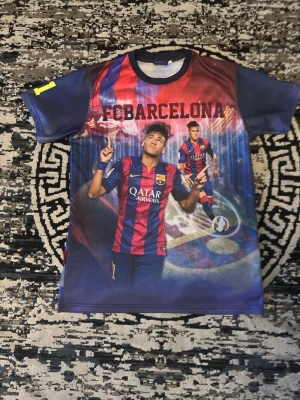 FC Barcelona t-shirt med Neymar Jr - Cool t-shirt med FC Barcelona-tema och Neymar Jr motiv. Tröjan har tryck i rött, blått och gult med klubbens logga och Qatar Airways sponsor. Perfekt för fotbollsfans som vill sticka ut på läktaren eller träningen.
