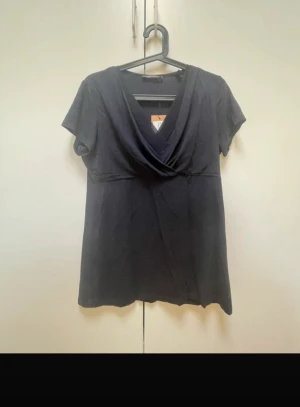 Svart omlottopp från Esprit - Svart topp från Esprit med snygg omlottdesign och v-ringning. Kortärmad modell i mjukt material som sitter bekvämt och passar till många olika stilar. Perfekt för dig som gillar en enkel men stilren look.