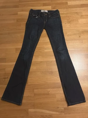 Mörkblå bootcut jeans Hollister - Snygga mörkblå bootcut jeans från Hollister. Jeansen är väldigt låtmidjade, och i suveränt skick. Storlek W 23, L 33.
