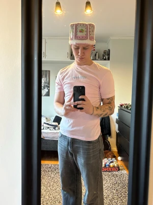 Ljus rosa T-shirt - Ljusrosa t-shirt med tryck. Klassisk passform och rund halsringning, perfekt för dig som gillar en enkel och clean look. Materialet är mjukt bomull som känns skönt mot huden. Snygg att matcha med jeans eller shorts.