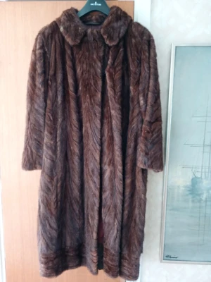 Brun vintage äkta mink  kappa - Snygg brun kappa i Minkpäls med klassisk krage och trekvartsärmar. Kappan har ett mönster i pälsen som ger en lyxig känsla och är perfekt för kalla dagar. Lång modell som ger en elegant siluett. Från 1970-1980 talet stl 38/40 .Bytt innefoder samt förläggning gjord någon gång . Päls Andersson i Mölndal . Arvegods,/dödsbo.