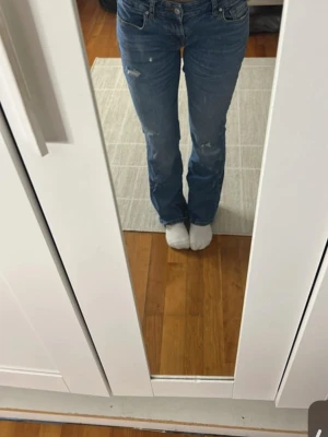 Blå slitna bootcut jeans  - Säljer ett par blå jeans med raka ben och slitna detaljer på låren och knäna. Jeansen har klassisk femficksmodell och normal midja. Perfekta för en avslappnad och trendig look. Pris kan diskuteras💗