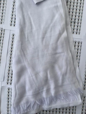 Vit sjal med fransar från cha nelle - Stilren vit sjal med tunna fransar längs ena kanten. Tillverkad i ett mjukt, vävt tyg som känns lätt och luftigt. Perfekt att slänga över axlarna för en fräsch look. Enkel design som passar till många outfits.