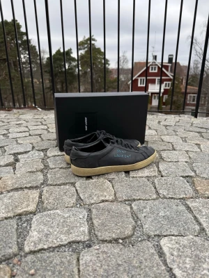 Saint Laurent Skor - Säljer dessa sjukt feta Saint Laurent skorna i svart färg med blå text! Storlek 43, ca 27cm på insidan. Perfekta nu till sommaren! Nypris på dessa är 7265kr. Box ingår ej. Självklart äkta! Hör av vid intresse eller frågor! Kan gå ner i pris vid snabb affär. Pris är ej hugget i sten!💯🍾🙌🏻