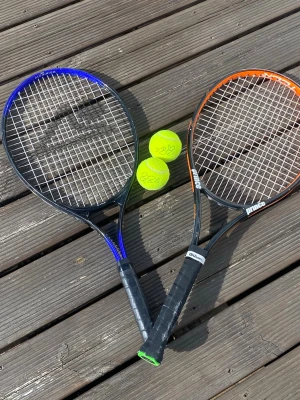 Orange Prince Wilson & Blå aluminium tennisracket använd i bra skick - Säljer ett tennispaket med två racketar, en från Head i svart och blått och en från Prince i svart och orange. Båda har svarta handtag och vita strängar. Två gula tennisbollar ingår. Perfekt för dig som vill komma igång med tennis eller spela med en vän.