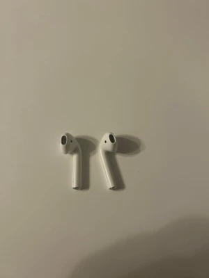 Apple AirPods trådlösa hörlurar - Säljer ett par vita Apple AirPods med stilren och minimalistisk design. De är helt trådlösa och har en slimmad form som sitter bekvämt i öronen. Perfekta för musik, poddar och samtal när du är på språng.2:a  Generationen.Finns även med C uttag.Äkta.