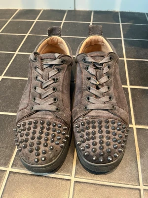 Gråa Louboutins - Säljer ett par gråa sneakers från Christian Louboutin, dom är väl andvända och har tappat några spikar men det är enkelt fix. Storlek 39