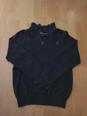 Mörkblå stickad tröja från Polo Ralph Lauren - Mörkblå långärmad tröja från Polo Ralph Lauren med quarter zip och broderad logga på bröstet. Tröjan är stickad och har en klassisk passform med hög krage. Perfekt för lager-på-lager och chill höst- och vinterstil. Axelbredd: 45cm / Längd: 60cm. Nypris: 2599kr / Mitt pris: 689kr