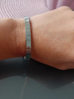 Silverfärgat armband med stenar - Nytt. Snyggt och stilrent armband i silverfärgad metall med infällda klara stenar runt om. Armbandet har en slät, polerad yta. Rostfritt stål. Nickelfritt 
