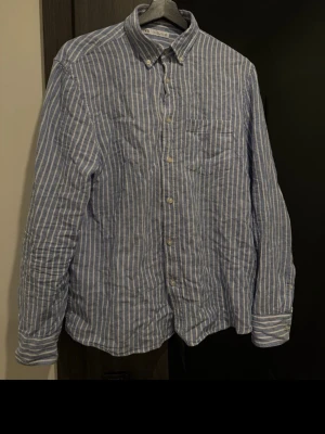 Blåvit randig skjorta från Zara - Säljer en snygg blåvit randig skjorta från Zara. Skjortan har klassisk krage, bröstficka och knappar framtill. Perfekt för dig som gillar en avslappnad men stilren look.
