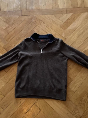 Mörkbrun Morris halvzip tröja i merinoull  - Mörkbrun långärmad tröja i merinoull  med halvzip och hög krage. Tröjan har en diskret logga på bröstet och ribbade muddar vid ärmslut och nederkant. Perfekt för lager på lager och en stilren look. Tröjan är från Morris och är äkta men har blivit krymt i tvätten, skulle säga den passar någon från ca 155 cm till ca 165 cm. Nypris är runt 2000 kr. Den är i fint skick utan några synliga defekter. Om du har några frågor är det bara att skriva.