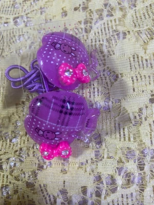 Söta hårklämmor med kaninmotiv - Två par plast hårklämmor i lila och rosa med gulliga kaninmotiv och små rosetter dekorerade med strasstenar. Perfekta för att piffa till frisyren med en lekfull och färgglad touch. Klämmorna har rundad form och är lätta att använda. 19kr/ par/ bild 