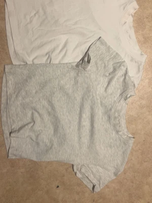 2-pack basic t-shirts från H&M - Säljer två basic t-shirts från H&M i storlek S. Ena t-shirten är helvit och den andra är ljusgråmelerad. Båda har rund halsringning och korta ärmar. Perfekta till alla outfits och superenkla att matcha. Materialet är mjuk bomull som känns skönt mot huden.