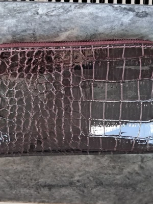 Sminkborsts fodral i mörklila krokodilmönster - Snygg sminkborsts fodral i mörklila, glansigt material med krokodilmönster. Fodralet har dragkedja och ger ett lyxigt intryck. Perfekt att ha i väskan för snabba touch-ups.