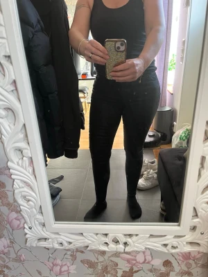 Svarta skinny jeans med hög midja - Säljer ett par svarta skinny jeans med hög midja och klassisk femficksdesign. Jeansen har en tight passform och är tillverkade i stretchigt material för en bekväm känsla. Perfekta för dig som gillar en stilren och modern look.