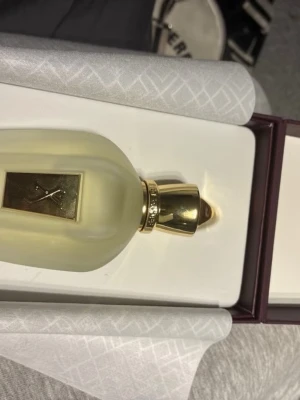 Xerjoff renaissance cologne - Exklusiv parfym från Xerjoff i en frostad glasflaska med gulddetaljer och elegant guldlock. Flaskan levereras i en lyxig ask med guldfärgat mönster och Xerjoff-logga. Perfekt för dig som gillar exklusiva dofter och snygg design.