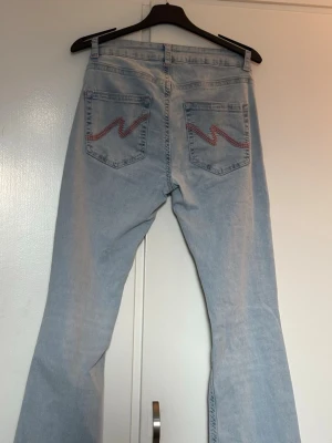 Ljusblå jeans från Nelly - Säljer ett par ljusblå jeans från Nelly med raka ben och slitningar vid knäna. De är använda fåtal gånger, dock finns det slitningar vid foten av byxbenen.