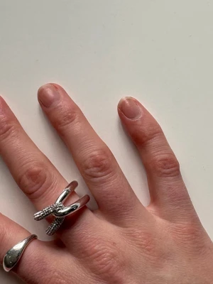 Silvrig ring med glittriga detaljer - Unik silvrig ring med en öppen design där ändarna är täckta av små glittrande stenar.      Helt ny! Nypris 499kr.                                       Storlek 19