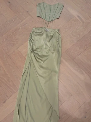 Ljusgrönt set från ohpolly - Snyggt ljusgrönt set från ohpolly i ett glansigt satinliknande material. Kjolen har en omlott-look med draperade detaljer och en elegant siluett. 