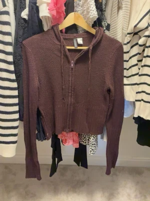 Brun röd  stickad hoodie med dragkedja - Mysig brun stickad hoodie från H&M med dragkedja framtill och långa ärmar. Tröjan har ribbade muddar och en avslappnad passform. Perfekt för lager på lager och chill dagar. Huva med dragsko för extra komfort.