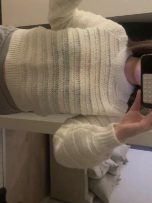 Vit ribbstickad tröja - Mysig vit stickad tröja med ribbade detaljer och rund hals. Tröjan har en croppad passform och långa ärmar med breda muddar. Perfekt för lager på lager och enkel att matcha till olika outfits.