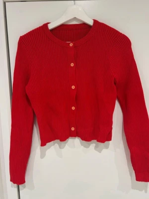 Stickad tröja - Röd stickad tröja med knappar. Finns matchande kjol. Använd 1 gång