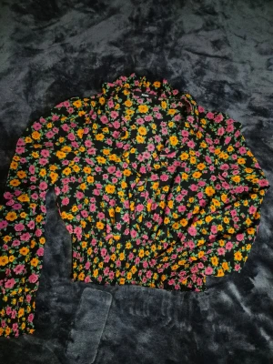 Blommig blus - Svart blus med färgglada blommor. Storlek M